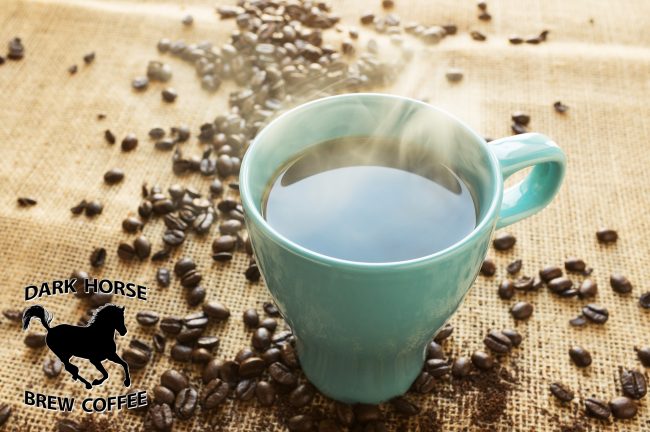 Banner of Green Mug with steaming coffee sitting on burlap fabric surrounded by scattered coffee beans.